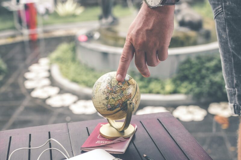 Osoba wskazująca palcem miejsce na małym globusie