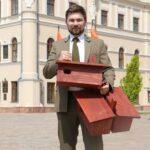 Pracownik Nadleśnictwa stojący na Rynku w Jarosławiu i trzymający budki dla jerzyków