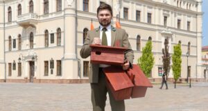 Pracownik Nadleśnictwa stojący na Rynku w Jarosławiu i trzymający budki dla jerzyków
