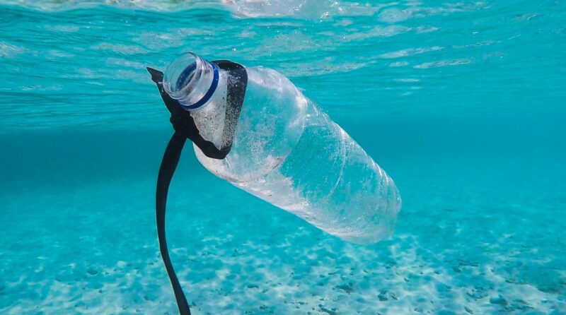Plastikowa butelka pływająca pod wodą turkusowego oceanu