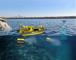 Żółto-czarna maszyna dryfująca po wodzie z dronem i sprzątająca dno oceanu