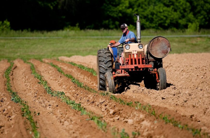 Rolnik na traktorze uprawiający pole, reprezentujący zmiany w polityce rolniczej UE.