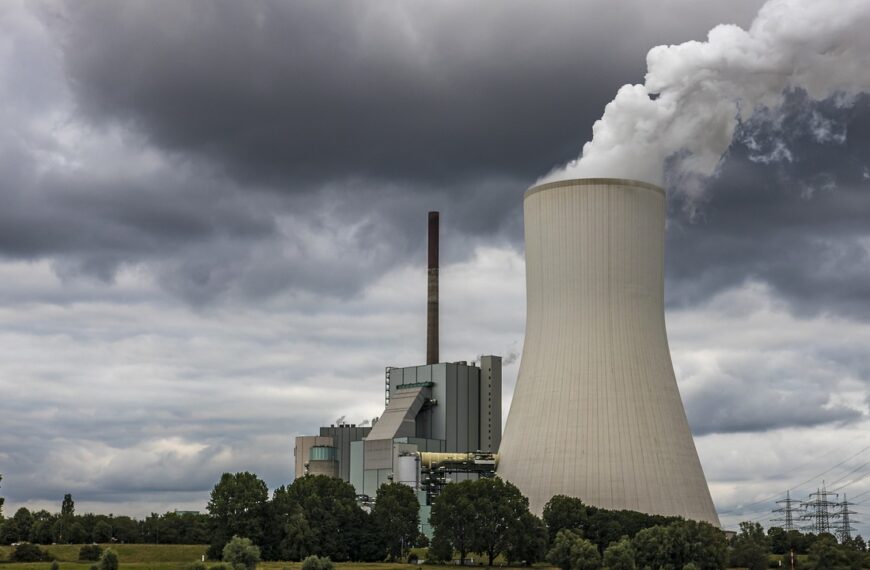 Elektrownia jądrowa z białymi chłodniami kominowymi na tle zachmurzonego nieba symbolizująca temat Szczytu Energii Jądrowej w Brukseli.